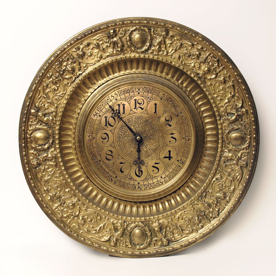 1888 GERMAN BRASS PLATE EMBOSSED WALL CLOCK: 1888 GERMAN BRASS PLATE EMBOSSED WALL CLOCK: Embossed frame featuring cherubs and foliate motif. Metal dial with Arabic numerals. Signed behind back plate Adolph Marjer?, Freidberg Hoefsen 1888. Lenzk