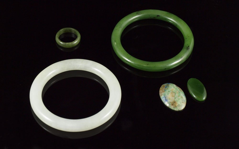 ESTATE LOT OF NEPHRITE JADE JEWELRY: ESTATE LOT OF NEPHRITE JADE JEWELRY: 5 pieces to include, Palest of grey green bangle, 2 3/8" interior, 3 1/4" dia., small natural crevasse at amber spot; Dark green bangle, 2 1/2" interior, 3 1/8"dia