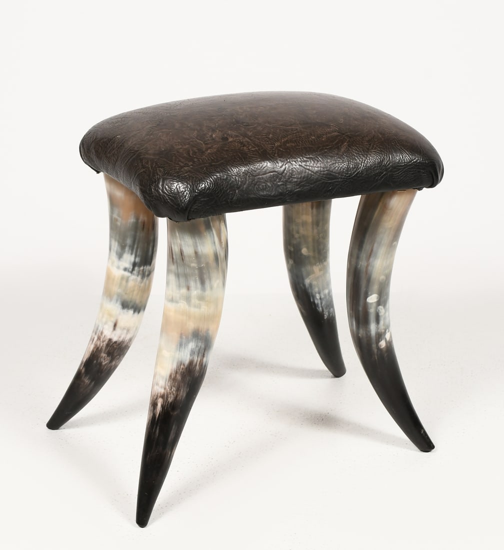 WENZEL FRIEDRICH STYLE COW HORN FOOTSTOOL: WENZEL FRIEDRICH STYLE COW HORN FOOTSTOOL: Handcrafted, ranch style footstool composed of leather upholstered cushion atop four large cattle horn legs. Approx. 19'' h x 19'' w x 12'' d.