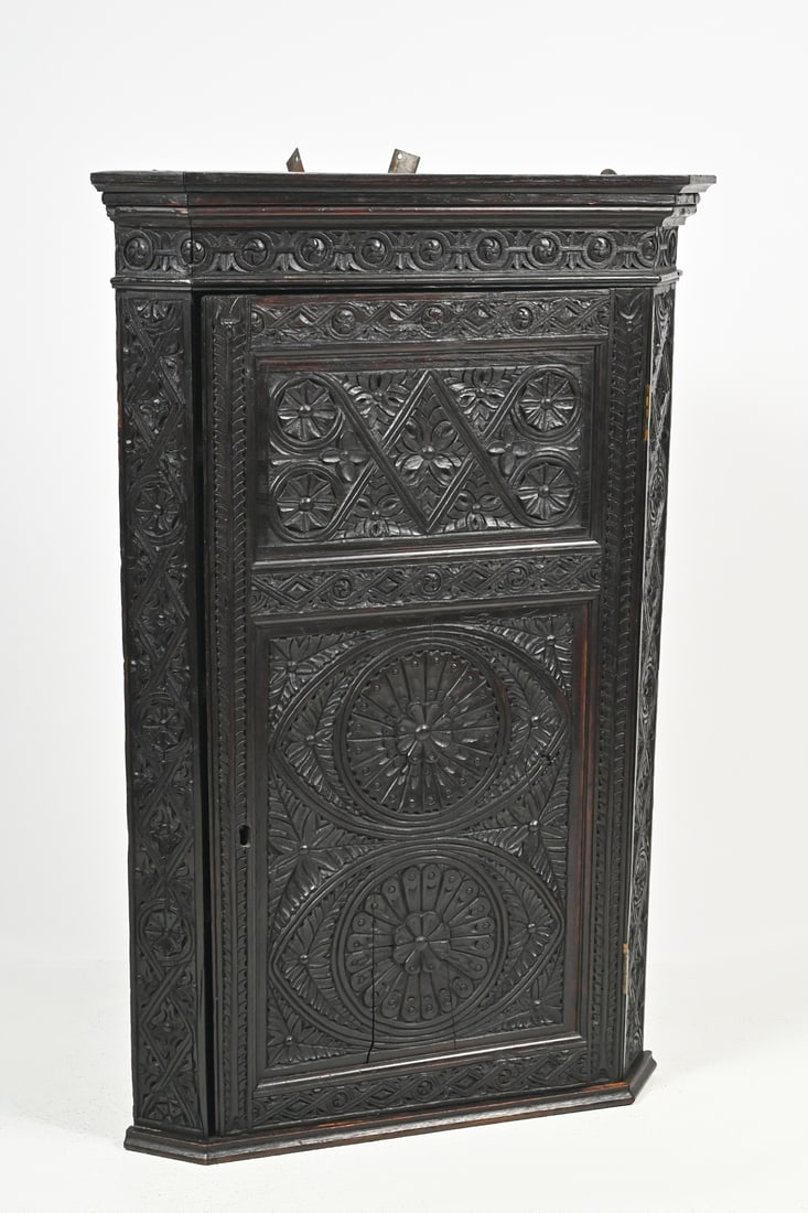 PROFUSLEY CARVED 18TH-CENTURY CORNER CUPBOARD: PROFUSLEY CARVED 18TH-CENTURY CORNER CUPBOARD: A hanging wall or freestanding corner cabinet with a dark finish, richly carved and having a single, locking door which opens to shelved interior. Approx