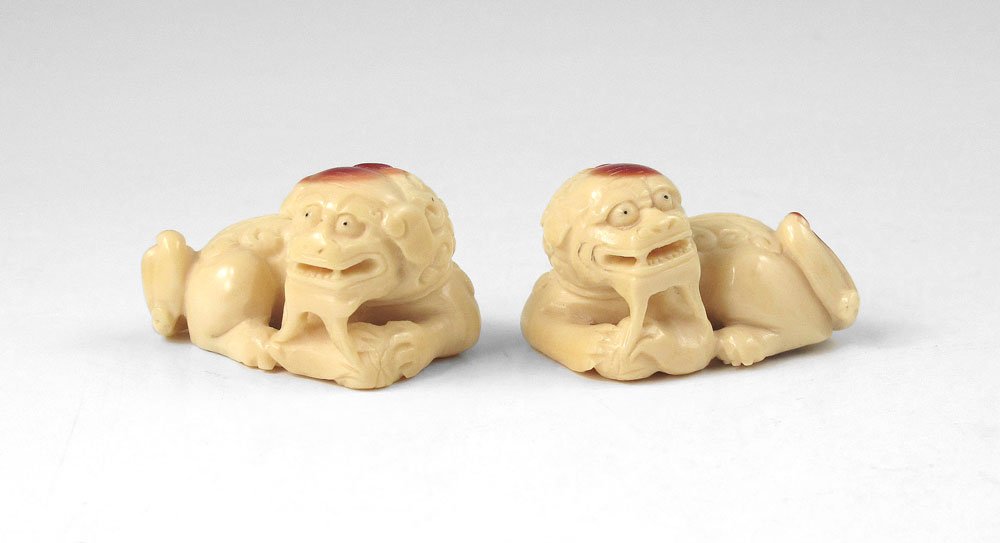 PAIR OF IVORY FOO LION NETSUKES: PAIR OF IVORY FOO LION NETSUKES: With red highlights, signed, 7/8"h. x 3/8" x 3/4"