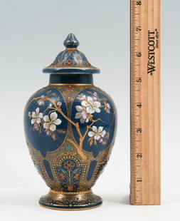 KPM ENAMELED LIDDED VASE: KPM ENAMELED LIDDED VASE: A baluster form KPM porcelain lidded vase, cloudy glazed in deep blue with relief gilt accents and polychrome enamels in a cherry blossom bough motif with geometric floral pa