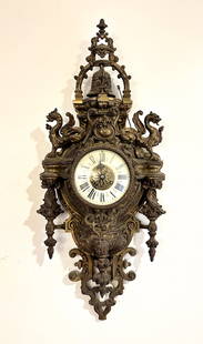 FIGURAL BRONZE CARTEL CLOCK: FIGURAL BRONZE CARTEL CLOCK: A magnificent French baroque bronze wall-mount cartel clock. Behind the convex glass dial door is an enameled chapter ring that glows under UV light, having black Roman