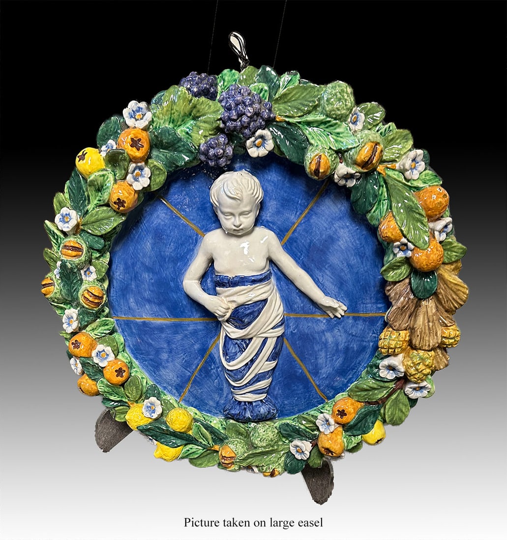 ITALIAN DELLA ROBBIA MAJOLICA ROUNDEL: ITALIAN DELLA ROBBIA MAJOLICA ROUNDEL: An Italian della Robia style majolica pottery tondo roundel depicting the robed Christ child within a wreathed border of colorful fruit, blossoms, & greenery in