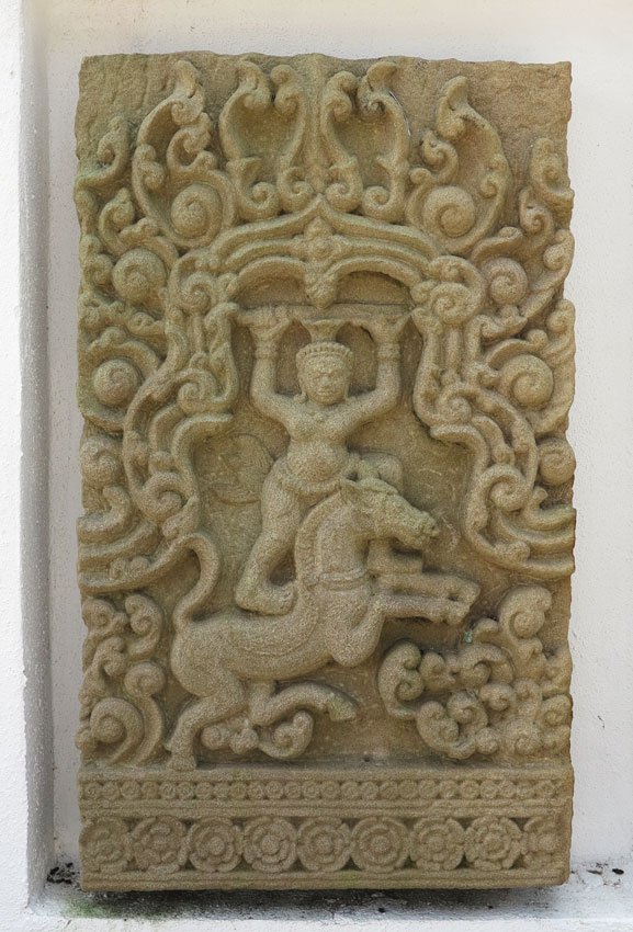 CAMBODIAN CARVED STONE FRIEZE: CAMBODIAN CARVED SANDSTONE FRIEZE: Frieze with high bas relief of warrior standing on charging horse in temple doorway within allover scrolls design on base floral border, 31'' high x 18'' wide x 3'' 
