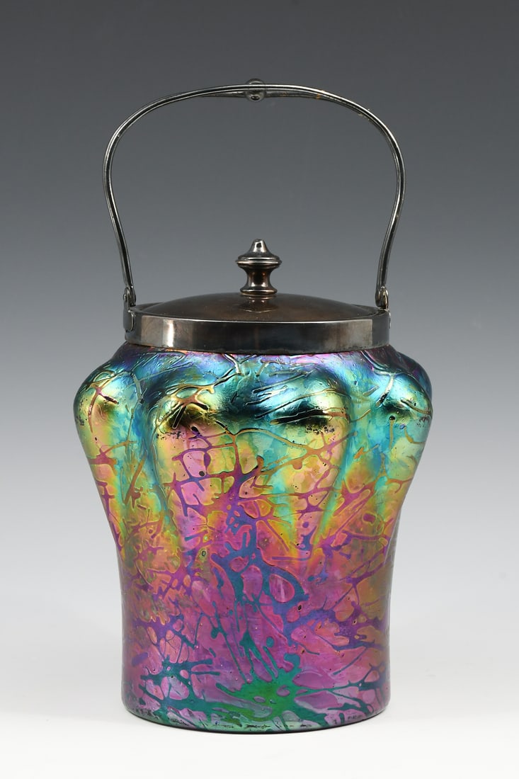 IRIDESCENT LOETZ ART GLASS BISCUIT JAR: IRIDESCENT LOETZ ART GLASS BISCUIT JAR: A colorful Loetz iridescent biscuit jar with raised teardrop sides. Silver plated collar, handle, & lid. Approx. 10.25" h x 6" w.