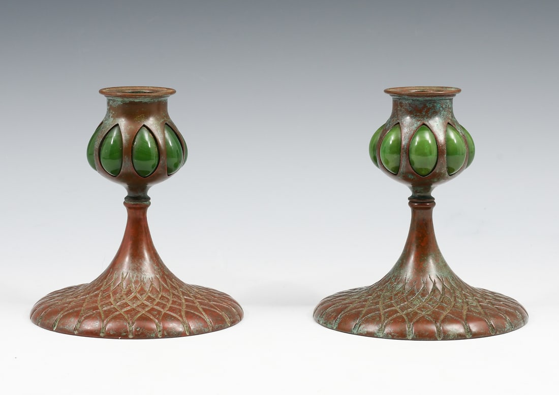 TIFFANY STUDIOS SIGNED BRONZE & GLASS CANDLESTICKS: TIFFANY STUDIOS SIGNED BRONZE & GLASS CANDLESTICKS: Tiffany Studios signed bronze candlesticks, having green blown glass, over a geometric motif. Signed at the undersides. Approx. 5.25" h x 4.75" Dia.