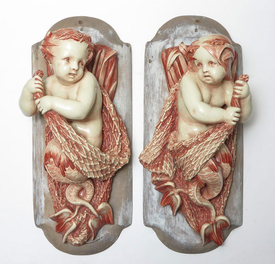 PAIR MINTON MERBABY MERMAN WALL BRACKETS: PR MINTON MERBABY WALL BRACKETS, Ca. 1881. Modeled as merbabies wrapped in fishing nets. Impressed Minton and date cypher mark of 1881. Mounted on partially painted, shaped wood plaques., 18.5'' x 7.5