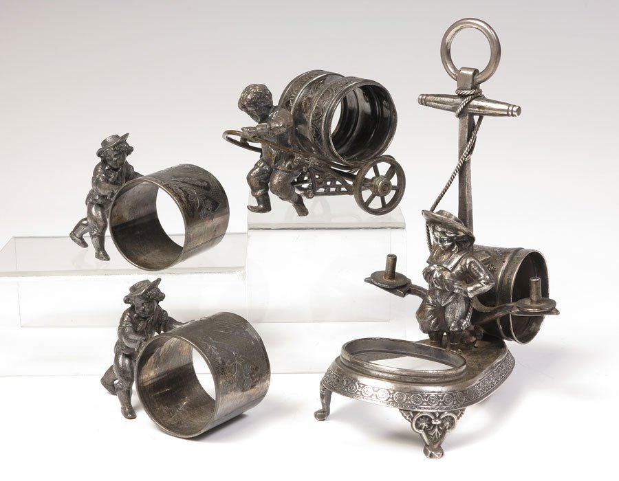 4 FIGURAL CHILDREN SILVERPLATE NAPKIN RINGS: 4 FIGURAL CHILDREN SILVERPLATE NAPKIN RINGS: 4 total pieces to include 1) Meriden child with anchor, ring on back condiment holder opening on front, no insert. #132, 7" h. x 5 1/4". 2) Boy pulling car