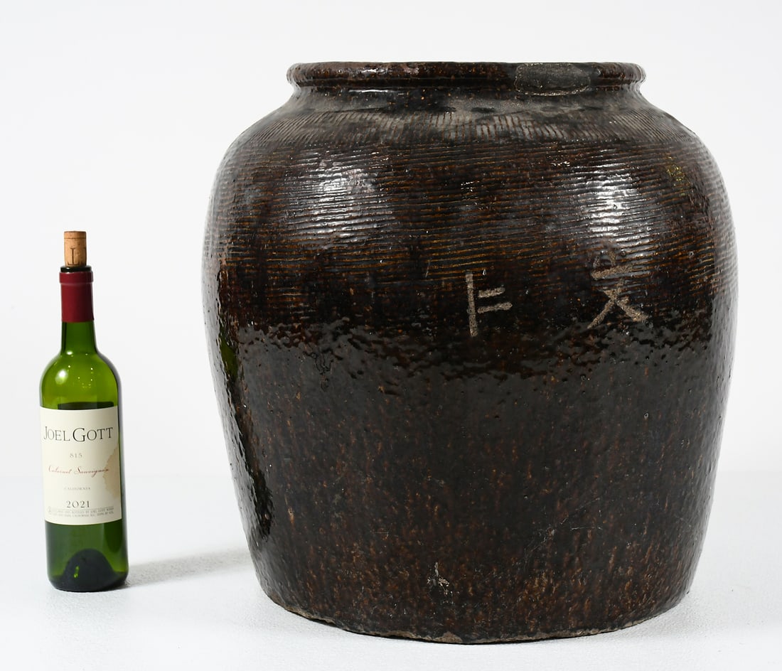 LARGE EARLY CHINESE BROWN GLAZED JAR: LARGE EARLY CHINESE BROWN GLAZED JAR: An early Chinese Earthenware Jar with an encompassing incised geometric design and two Chinese Characters. Approx. 19" h x 19.5" dia.