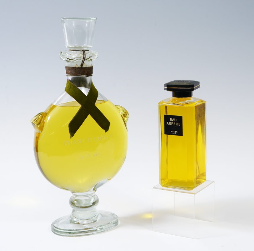 2 PIECE LANVIN & GUERLAIN FACTICE PERFUME BOTTLES: 2 PIECE LANVIN & GUERLAIN FACTICE PERFUME BOTTLES: To include 1) "Eau Arpege" by Lanvine Paris, 9" h. x 3 3/8" x 3 3/8". 2) "Chante D'Aromes" by Guerlain, chip to base, wear to lettering, 18 1/2" h. x