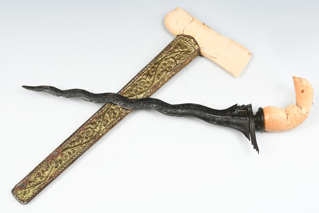 KERIS KNIFE W/ TOOLED METAL SHEATH: KERIS KNIFE W/ TOOLED METAL SHEATH: Wavy blade keris ("kriss") knife with carved mammoth tusk handle. Sheath has a mammoth tusk core covered by tooled metal overlay. Blade measures 12.5" in length; ov