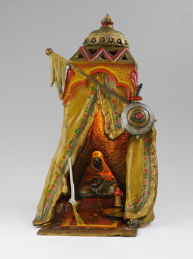 BERGMAN STYLE AUSTRIAN COLD PAINTED LAMP: BERGMAN STYLE AUSTRIAN COLD PAINTED LAMP: Orientalist motif with Arab man playing instrument inside tent with shield and flag. 13'' h. x 8 3/4'' x 7 1/4''.