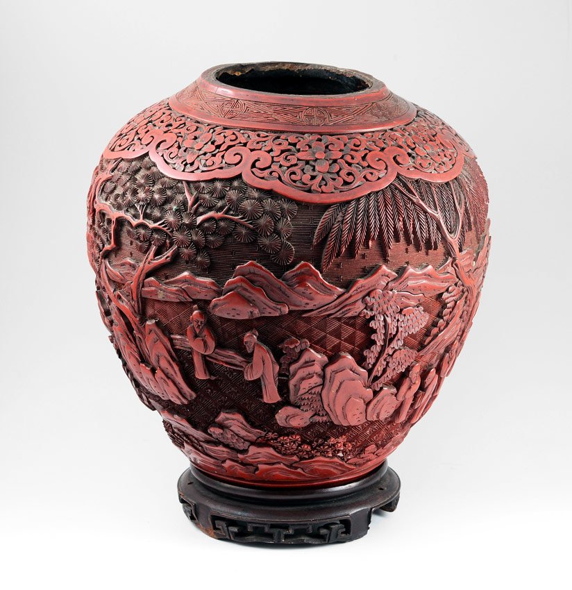1920'S CINNABAR VASE: 1920'S CINNABAR VASE: Carved with figures in mountainous landscape. Missing bottom, may have been converted to lamp at some point. 9 1/2" h. x 9" dia. Sold with carved wood stand 5 1/2" dia.