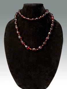 CHERRY AMBER BEADS: CHERRY AMBER BEADS: A hand tied strand of graduated oval faceted beads of cherry amber. Length: approximately 34".