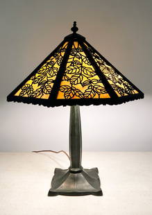 PATINATED METAL FILLIGREE SLAG GLASS TABLE LAMP: PATINATED METAL FILLIGREE SLAG GLASS TABLE LAMP: Metal table lamp with leaf-pattern filigree shade holding slag glass panels. Measures 21” in height overall. Shade measures 17” wide.
