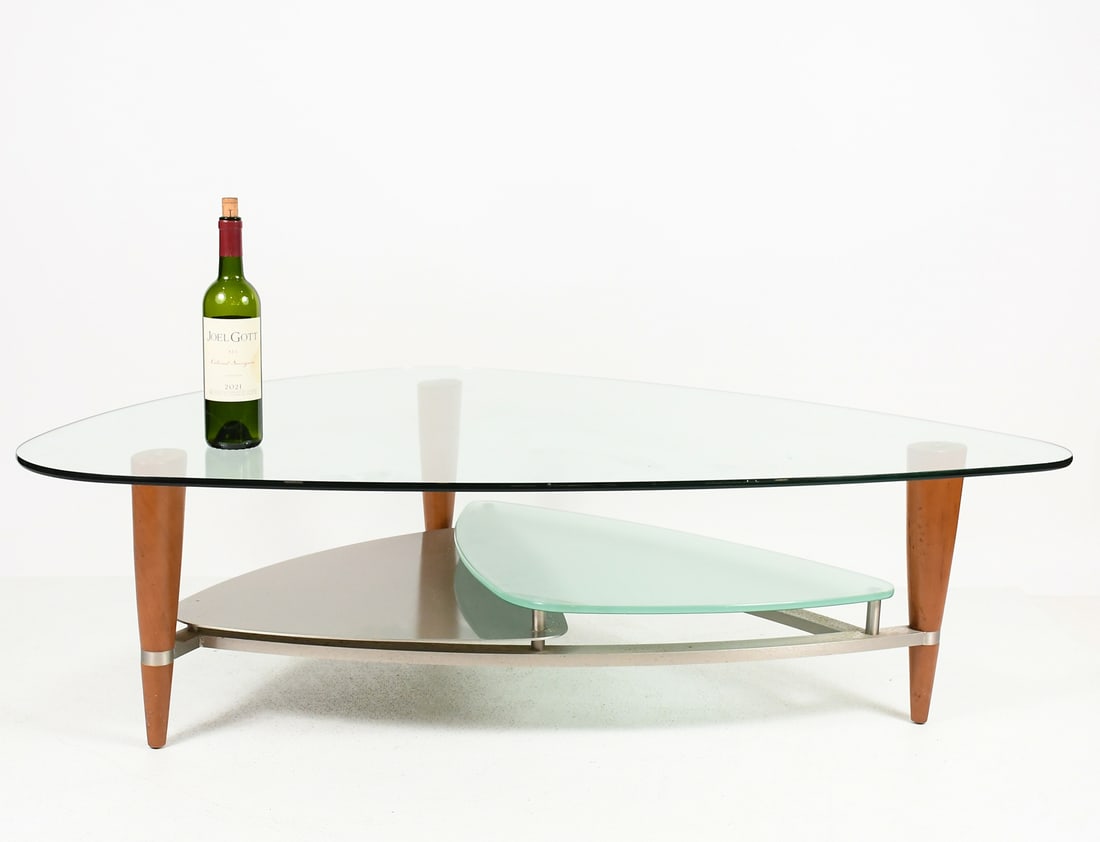 MODERN SCANDANAVIAN TRIANGULAR GLASS COFFEE TABLE: MODERN SCANDANAVIAN TRIANGULAR GLASS COFFEE TABLE: A 3- tiered Glass top Triangular Coffee Table with a Brushed Stainless frame & lower shelf. Raised on tapered legs. Approx. 16.25" h x 56.25" l x 36.