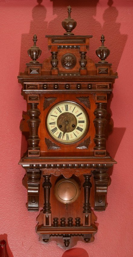GERMAN CARVED WALL CLOCK: GERMAN CARVED WALL CLOCK: Removable architectural crest with 3 finials. Case with applied carved decoration. Dial with embossed floral center, porcelain ring with Roman numerals. Key wind time and str