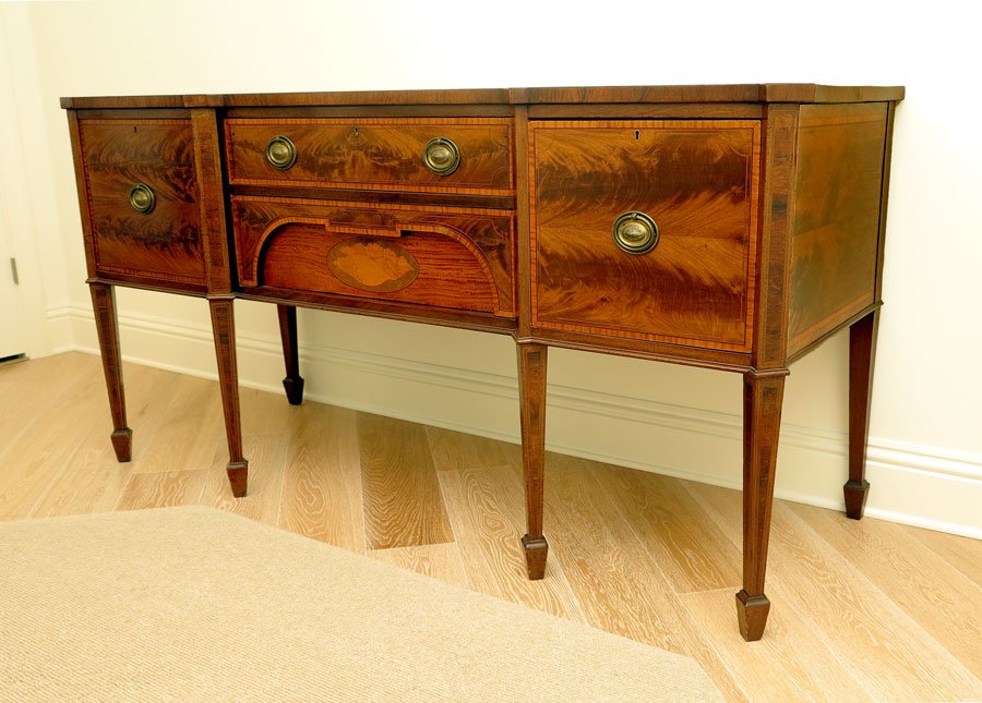 HEPPLEWHITE STYLE INLAID WALNUT SIDEBOARD:: HEPPLEWHITE STYLE INLAID WALNUT SIDEBOARD: Shaped top with string inlay. 2 central drawers with lower drawer having shell marquetry inlay. Right side with deep compartmented wine drawer, left side sin