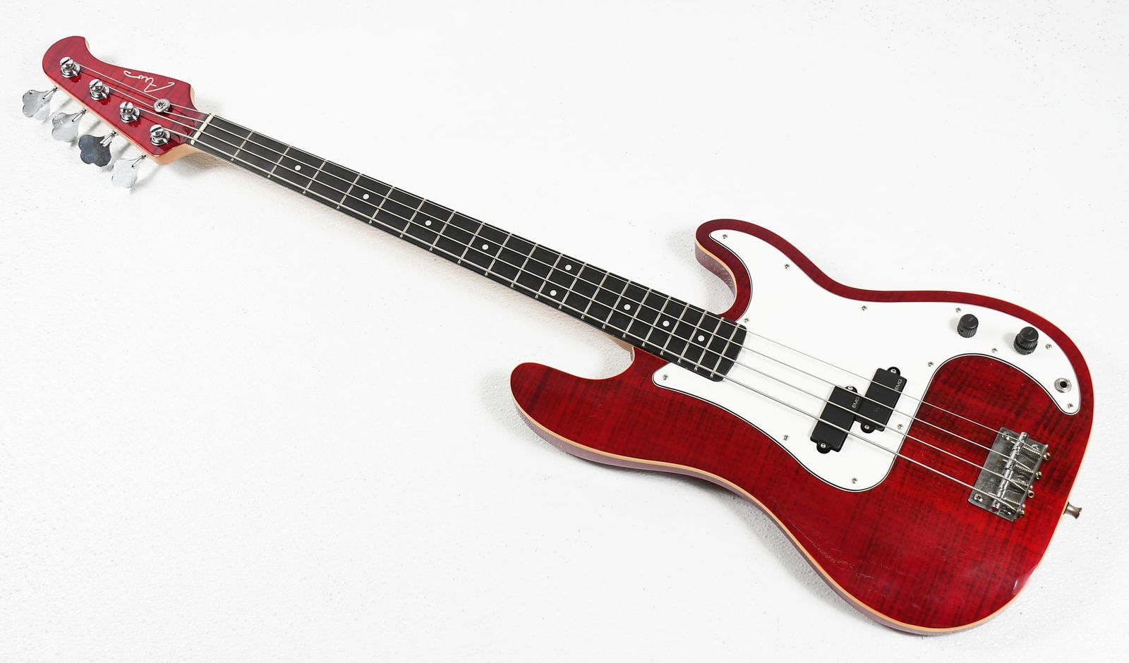 AIO ELECTRIC BASS GUITAR: AIO ELECTRIC BASS GUITAR: Red Wine Mahogany body with a Tiger Maple top, EMG pickups, Grover tuning pegs. Rests in a AIO soft case. Approx. 45.75" l. Provenance: Estate of Ed Hauser, Bassist for the 8