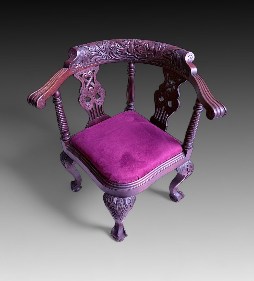 CARVED CORNER CHAIR: CARVED CORNER CHAIR: Ornately carved wooden corner chair with curling armrests, twisting support columns, and clubbed feet. Measures 30.25" (h) x 29.5" (w) x 26.5" (d).