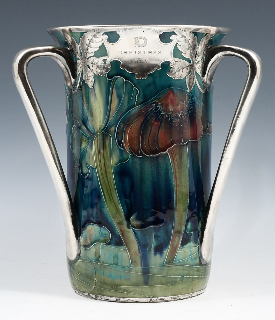 MOORCROFT CLAREMONT STERLING MOUNTED VASE: MOORCROFT CLAREMONT TRI-HANDLED STERLING MOUNTED VASE: An impressive Moorcroft loving cup in the Claremont design on green ground with three applied handles and flared rim. Sterling overlay rim, handl