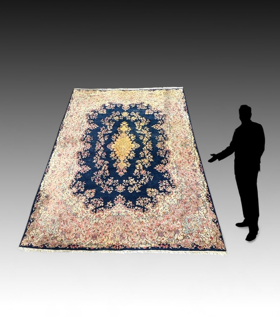 ESTATE ORIENTAL PERSIAN KERMAN DESIGN CARPET: ESTATE ORIENTAL PERSIAN KERMAN DESIGN CARPET: A large Persian carpet that has a dark blue field with a yellow tone center medallion the balance of the rug is populated with a floral/foliated design in