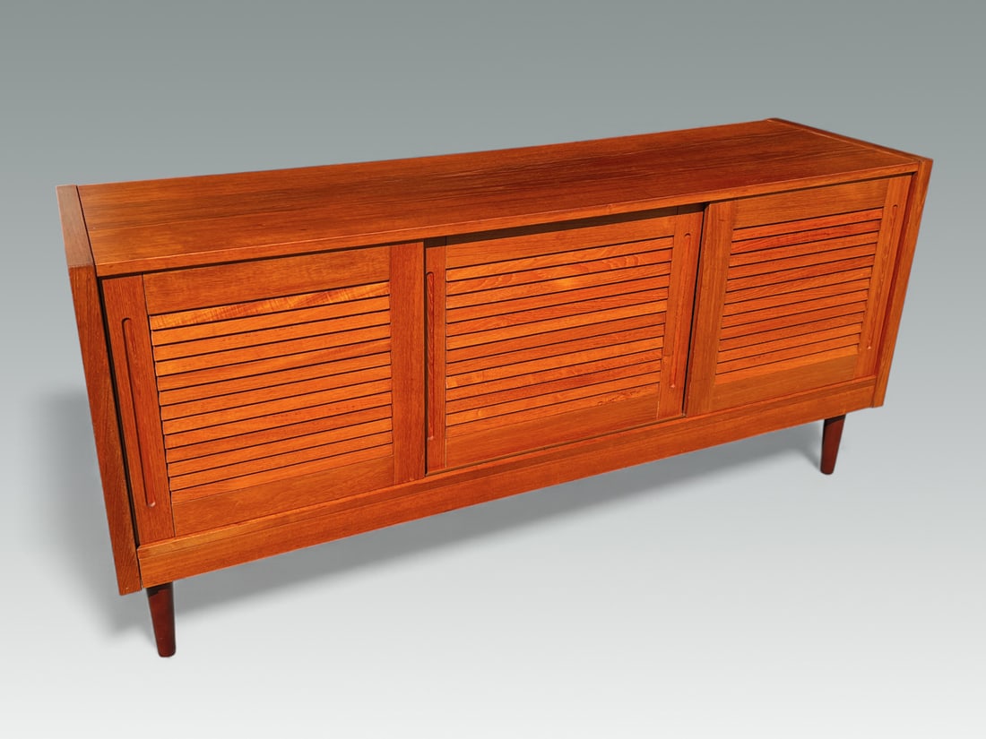 MCM DANISH TEAK CREDENZA/SERVER: MCM DANISH TEAK CREDENZA/SERVER: Danish mid-century modern Teak Credenza with three louvered sliding doors. Three utensil drawers reside behind the left drawer. Raised on tapered round legs. Approx. 2