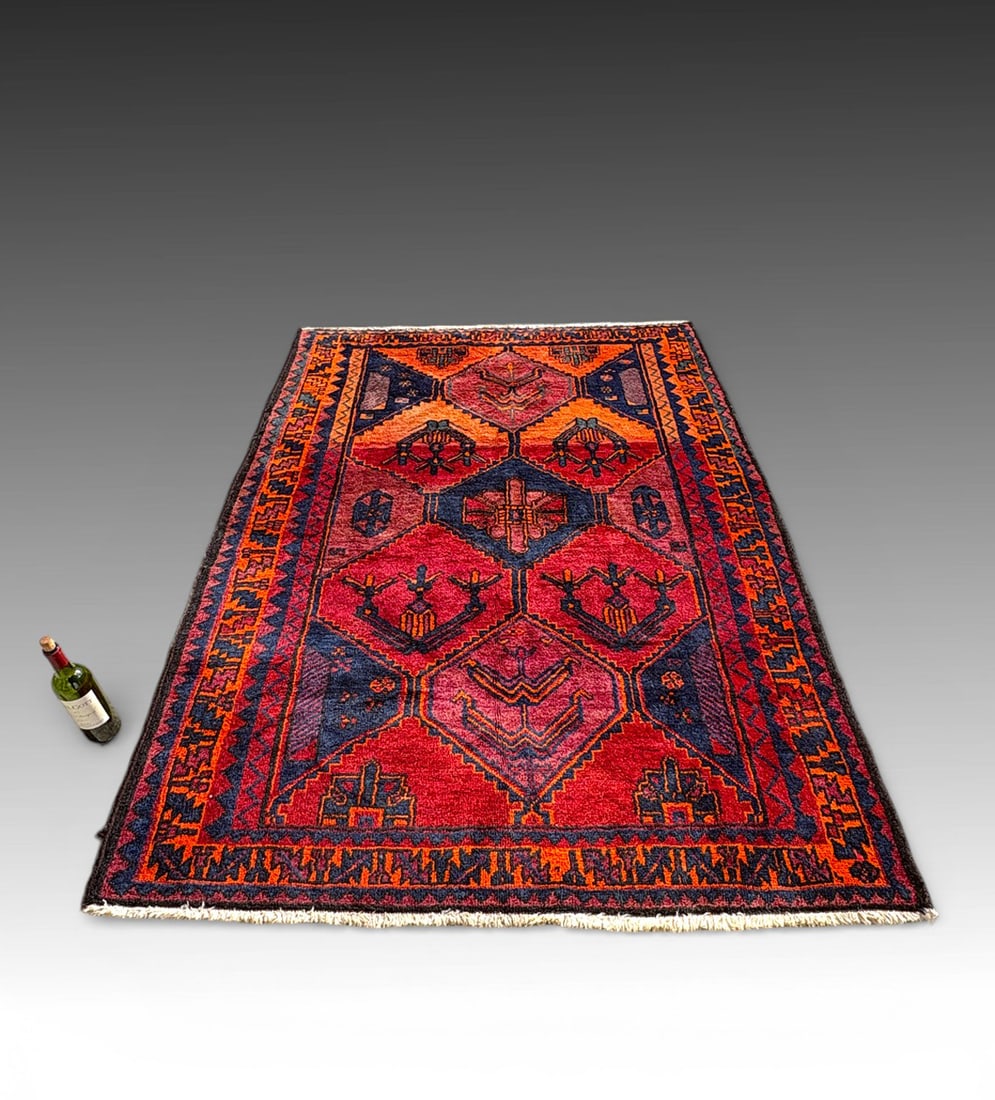 ANTIQUE PERSIAN DESIGN TRIBAL WOOL RUG: ANTIQUE PERSIAN DESIGN TRIBAL WOOL RUG, C. 1880–1900: Featuring a dynamic field of interconnected hexagonal compartments filled with stylized symbolic and geometric motifs. The rug is rendered in a