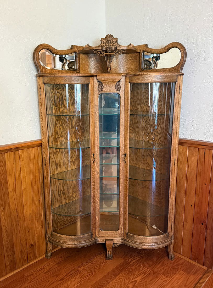 ART NOUVEAU / VICTORIAN TIGER OAK CORNER CABINET: ART NOUVEAU / VICTORIAN TIGER OAK CORNER CABINET: An Art Nouveau / Late Victorian quarter-sawn tiger oak corner curio cabinet, circa 1900, featuring a serpentine front with curved glass sides, shaped