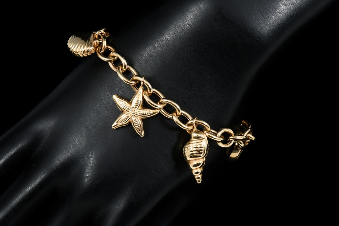 14K GOLD OCEAN THEMED CHARM BRACELET: 14K GOLD OCEAN THEMED CHARM BRACELET: 14K yellow gold bracelet with 6- 14K yellow gold charms in the form of sea shells and ocean creatures. Length: approximately 7.5". Weight 13.2 grams.