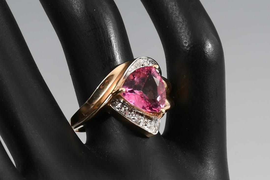 14K PINK TOPAZ RING: 14K PINK TOPAZ RING: 14 karat bypass yellow gold pink topaz and diamond ring. Trillion cut, treated, 3.0 carats. 5 round full cut diamonds @ 0.05 CTW. rated H-I in color and SI-2 to I-1 in clarity. To