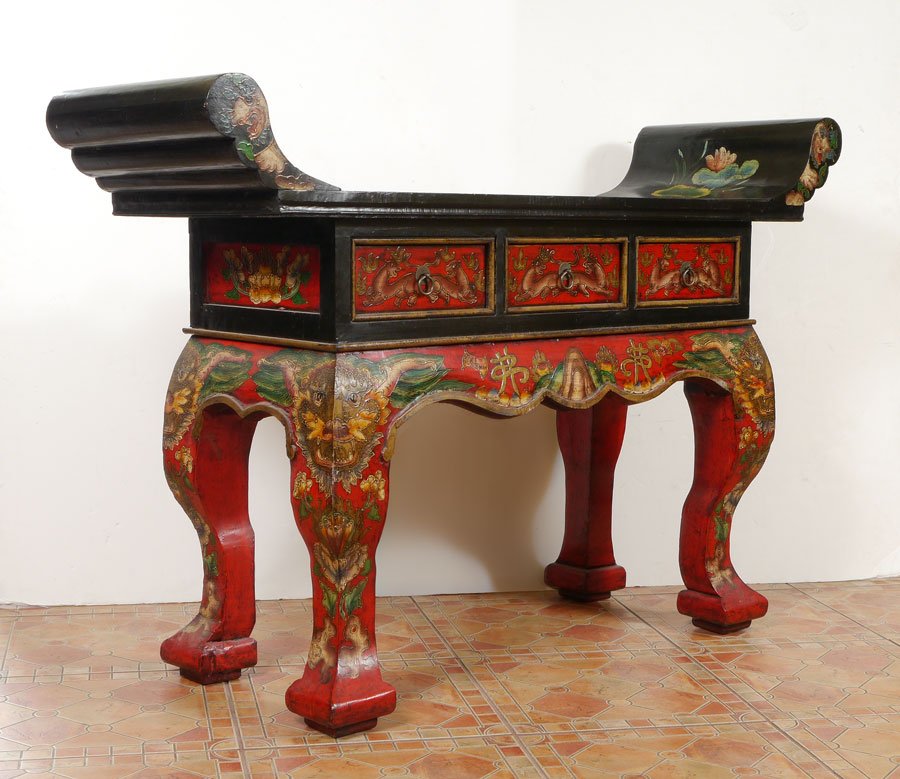 PAINT DECORATED CHINESE ALTAR TABLE: PAINT DECORATED CHINESE ALTAR TABLE: Black lacquer top, red lacquer base with floral motif all over, masquerons at top of legs. Shaped top over 3 drawers, shaped legs. Age unknown. 38'' h. x 56'' x 17