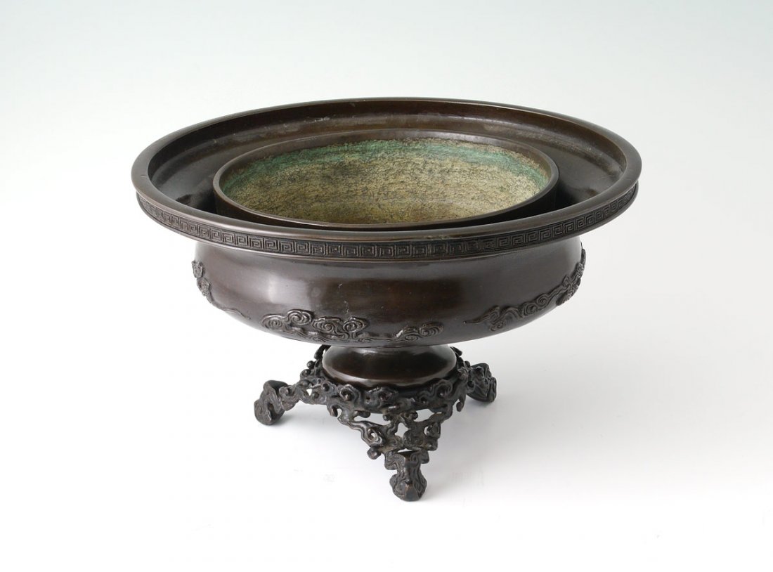 MEIJI PERIOD JAPANESE BRONZE PLANTER ON STAND: MEIJI PERIOD JAPANESE BRONZE PLANTER ON STAND: Bowl form planter with applied decoration on side, signed on base. Sets into ornate bronze tri foot stand. Overall measures 5 1/2'' h. x 9 1/4''.