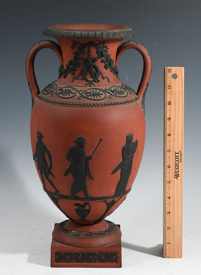 WEDGWOOD ROSSO ANTICO "PROCESSION OF DEITIES" VASE: WEDGWOOD ROSSO ANTICO "PROCESSION OF DEITIES" VASE: 1790-1810, Two-handled terracotta Wedgwood vase with black relief figures mounted on a socle, decorated with a frieze of the procession and classica