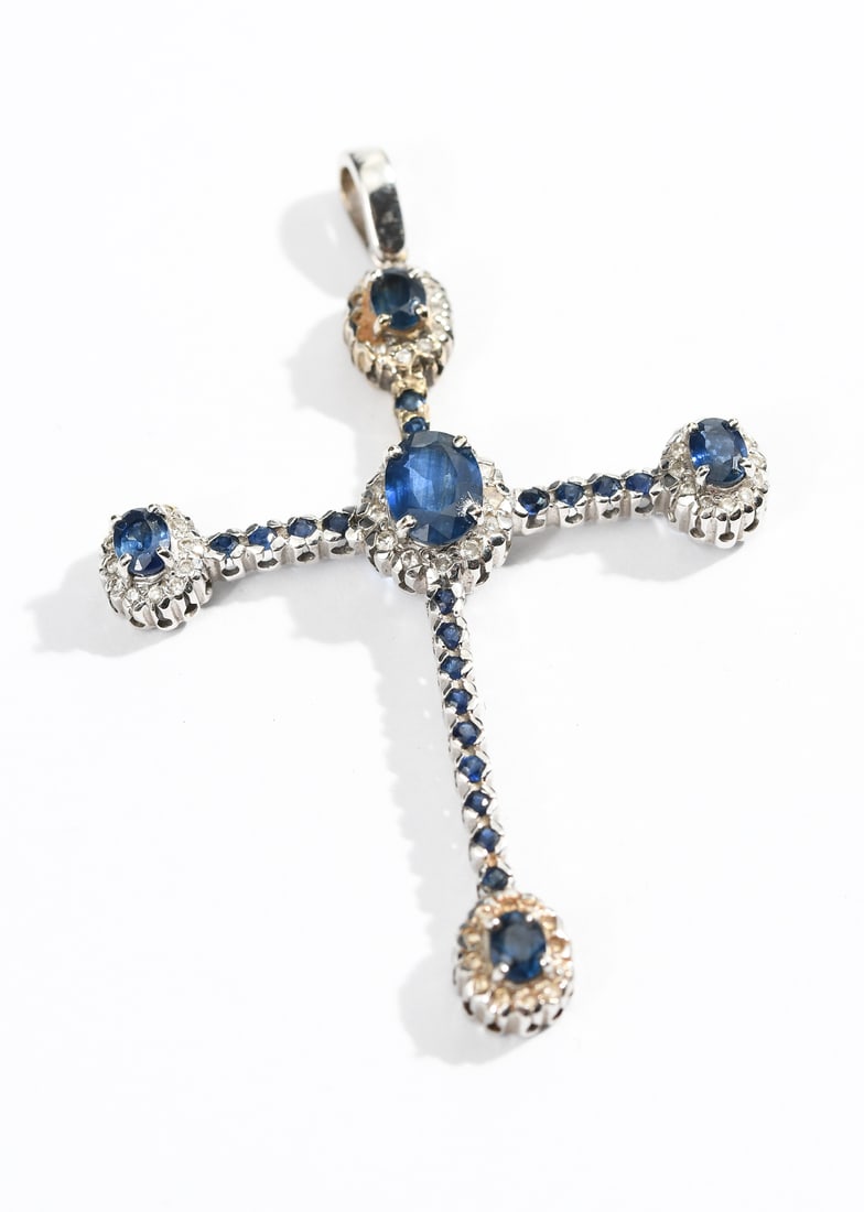 18K SAPPHIRE & DIAMOND CROSS PENDANT: 18K SAPPHIRE & DIAMOND CROSS PENDANT: 18K white gold cross pendant contains 5 oval and 19 round mixed cut sapphires. Weight: 3.50 Ct. Approx. Rated VS in clarity (Type II), B in Hue, 7 in Tone and 3 i