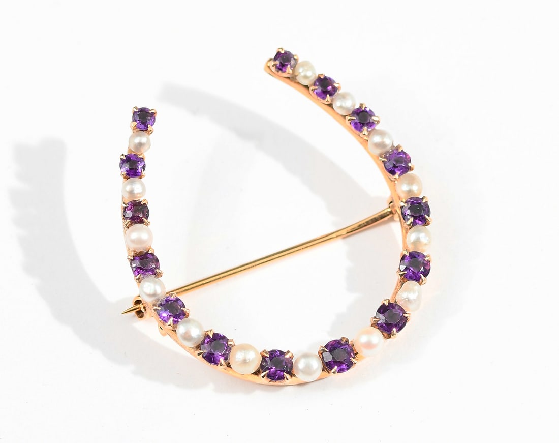 14K AMETHYST/PEARL HORSESHOE BROOCH: 14K AMETHYST/PEARL HORSESHOE BROOCH: 14K yellow gold horseshoe brooch contains 15 round mixed cut amethyst. Weight: 1.00 Ct. Approx. The amethyst are prong set, seed pearls are peg and epoxy set. Lock