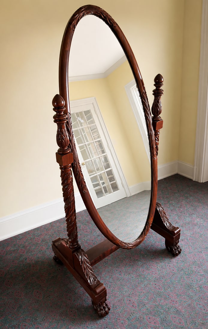 CARVED MAHOGANY CHEVAL MIRROR: CARVED MAHOGANY CHEVAL MIRROR: Carved Acanthus motif, raised on paw feet with casters. Approx. 70.5" h x 35.25" w x 24.5" d.