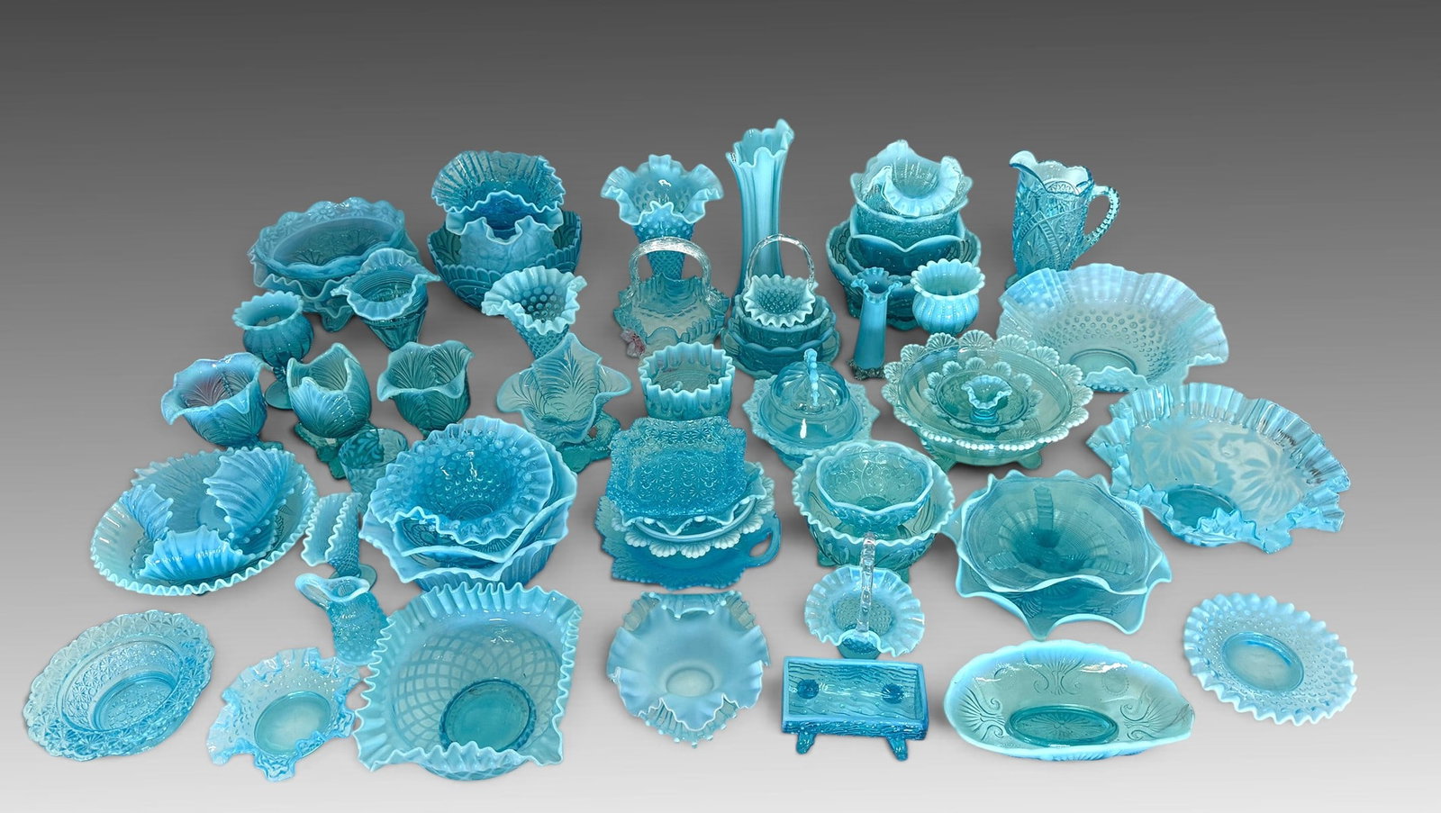MASSIVE COLLECTION OF BLUE OPALESCENT GLASS: MASSIVE COLLECTION OF BLUE OPALESCENT GLASS: Several hobnail pieces, Multiple Ruffled Bowls and Vases, Brides Baskets, Compotes, and Covered Dishes. Pieces in patterns that resemble makers such as Fen