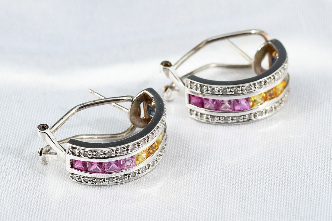 14K MULTI-STONE EARRINGS: 14K MULTI-STONE EARRINGS: One pair of 14K white gold pierced clip back shrimp style ear hoops. Each hoop is centered by an inline row of channel set Princess cut natural mined Sapphires in a graduatin