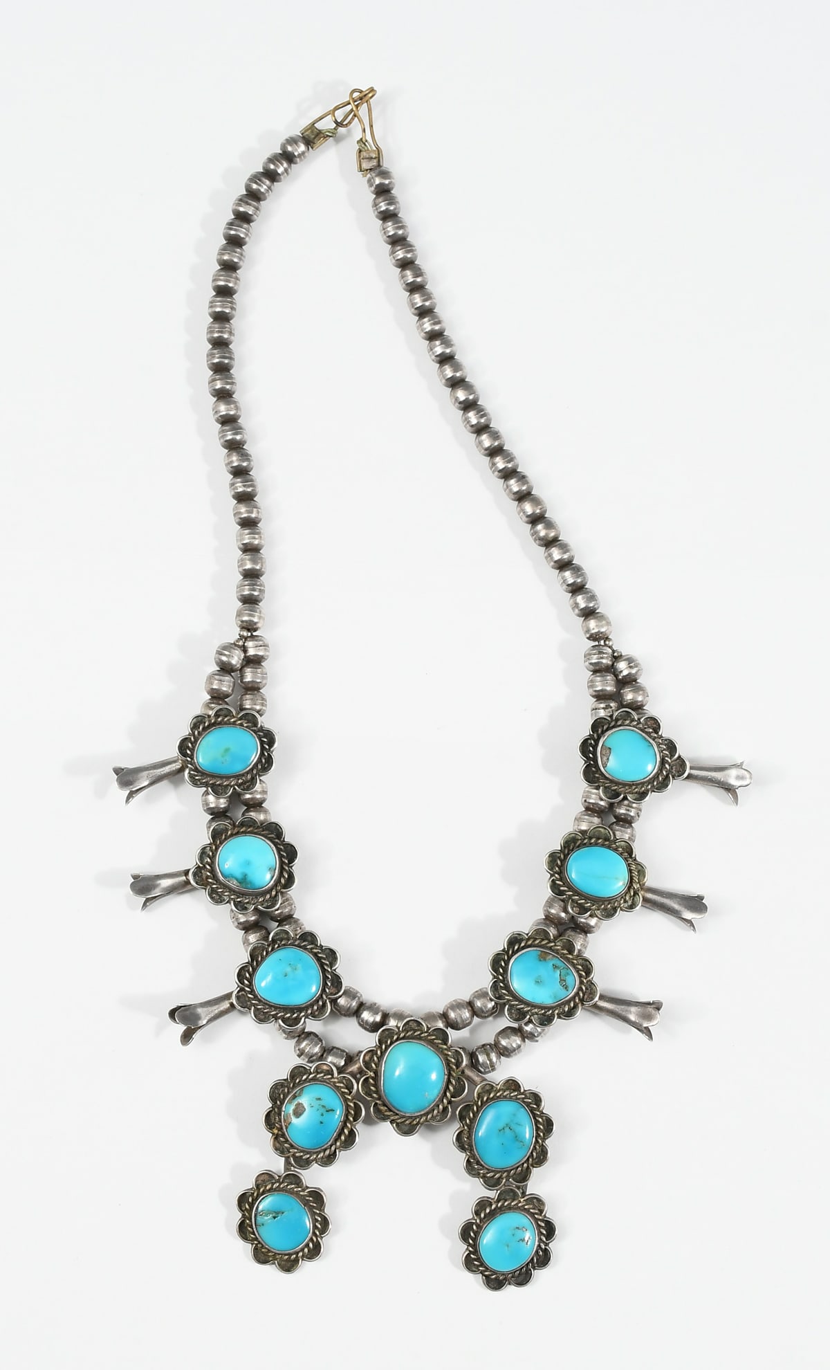 SQUASH BLOSSOM STERLING NECKLACE: SQUASH BLOSSOM STERLING NECKLACE Handmade Native American squash blossom necklace crafted in sterling silver with natural turquoise stones. This vintage, antique necklace features beaded construction,