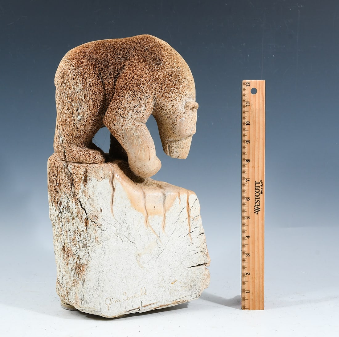 FOSSILIZED WHALE BONE INUIT CARVED BEAR ON CLIFF: FOSSILIZED WHALE BONE INUIT CARVED BEAR ON CLIFF: A carved whalebone sculpture of a Bear on a cliff, handcrafted by Jim Correll for Ekemo Studios of Eagle River, Alaska. Signed at lower side. Approx. 