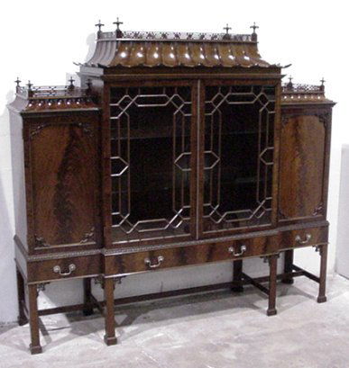 CHINESE CHIPPENDALE CURIO CABINET: ELEGANT CROTCH GRAIN MAHOGANY ORIENTAL CURIO IN THE MANNER OF THOMAS CHIPPENDALE: Pierced carved gallery with inverted finial carvings. Concave fluted pagoda tops to cabinet sections over 4 door cabin