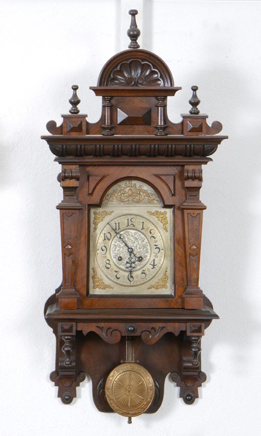 CARVED GERMAN WALL CLOCK: CARVED GERMAN WALL CLOCK: Carved and applied decoration all over. Removable pediment. Mixed metal dial with Roman numerals. Key wind time and strike movement, embossed pendulum. 34"h. x 16 3/4" x 8".