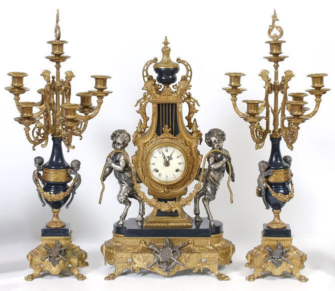 3 PIECE IMPERIAL FIGURAL CLOCK GARNITURE SET: 3 PIECE IMPERIAL FIGURAL CLOCK GARNITURE SET: Ornate case with figural pan children holding rope with floral swag standing on enamel over cast base. Porcelain dial marked Imperial, Made in Italy. Key