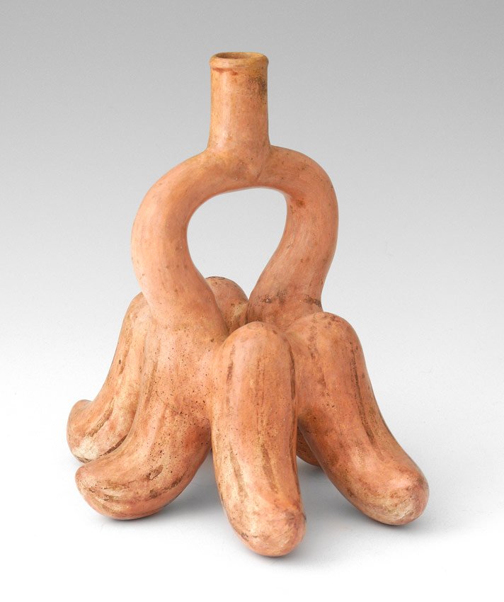 MOCHICA REDWARE CERAMIC STIRRUP SPOUT VESSEL: UNUSUAL MIDDLE MOCHICA SALMON-PINK GLAZED REDWARE CERAMIC STIRRUP SPOUT VESSEL: Peru, circa A.D. 200-500, molded in the form of six upright peppers, the stirrup handle issuing from the two side pepper