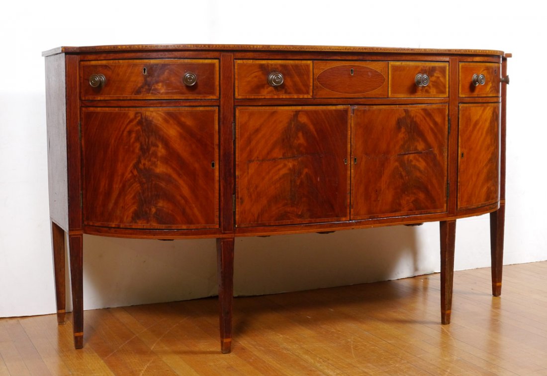 HEPPLEWHITE STYLE INLAY MAHOGANY SIDEBOARD: HEPPLEWHITE STYLE INLAY MAHOGANY SIDEBOARD: Shaped top with banded inlay trim, 3 drawers over 4 doors with string inlay on all. Drawers with chamfered bottoms. Tapered legs. Measures 38 3/4" h. x 70" 