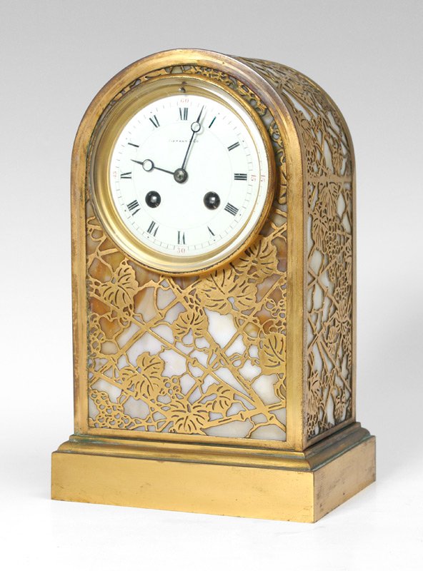 TIFFANY STUDIOS GRAPEVINE PATTERN MANTLE CLOCK: TIFFANY STUDIOS GRAPEVINE PATTERN MANTLE CLOCK: Mantle or desk clock from Tiffany Studios with Grapevine pattern gilt metal over caramel slag glass case with the rarer and elusive domed top. Case mark