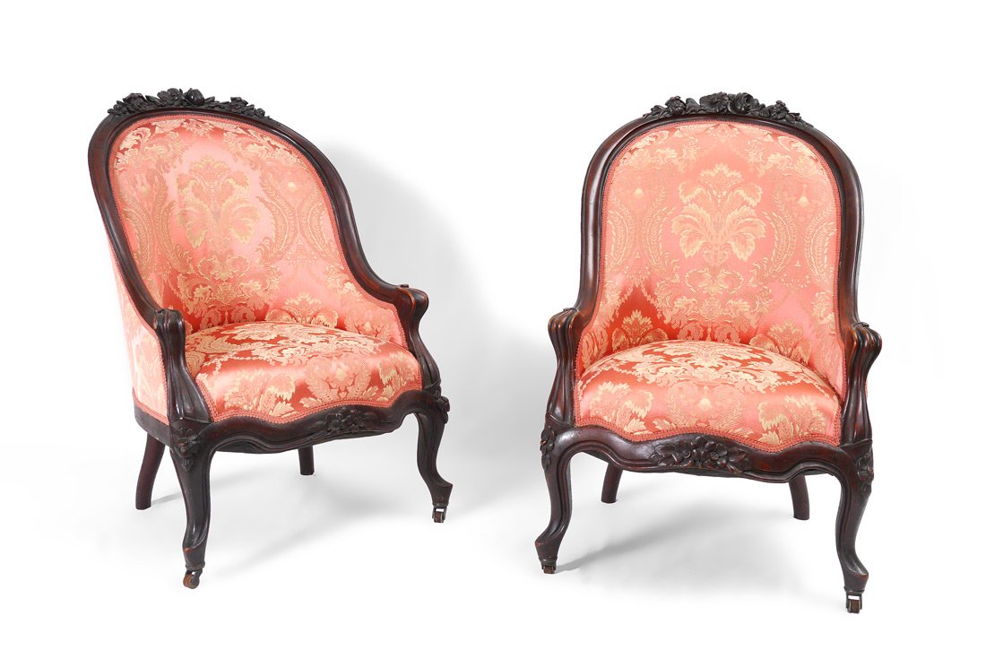 PAIR CARVED VICTORIAN SLIPPER CHAIRS: PAIR CARVED VICTORIAN SLIPPER CHAIRS: Carved top rail with floral motif, shaped arms. Carved and shaped hand holds, skirt and front legs ending in castors. Pink foliate upholster front and back. 35 3/