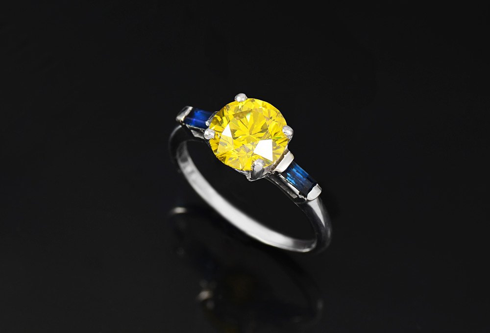 PLATINUM 2.3 CT YELLOW DIAMOND SOLITAIRE RING SZ 7: PLATINUM 2.3 CT YELLOW DIAMOND SOLITAIRE RING: Fancy intense yellow round brilliant diamond, approx. 2.30 Ct, measures 5.27 mm. Clarity is VS1. There are two baguette cut sapphires at the sides, each 
